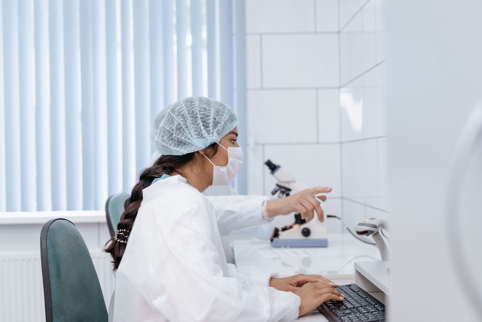Female scientist in laboratory coat working at computer in a clean, modern lab.