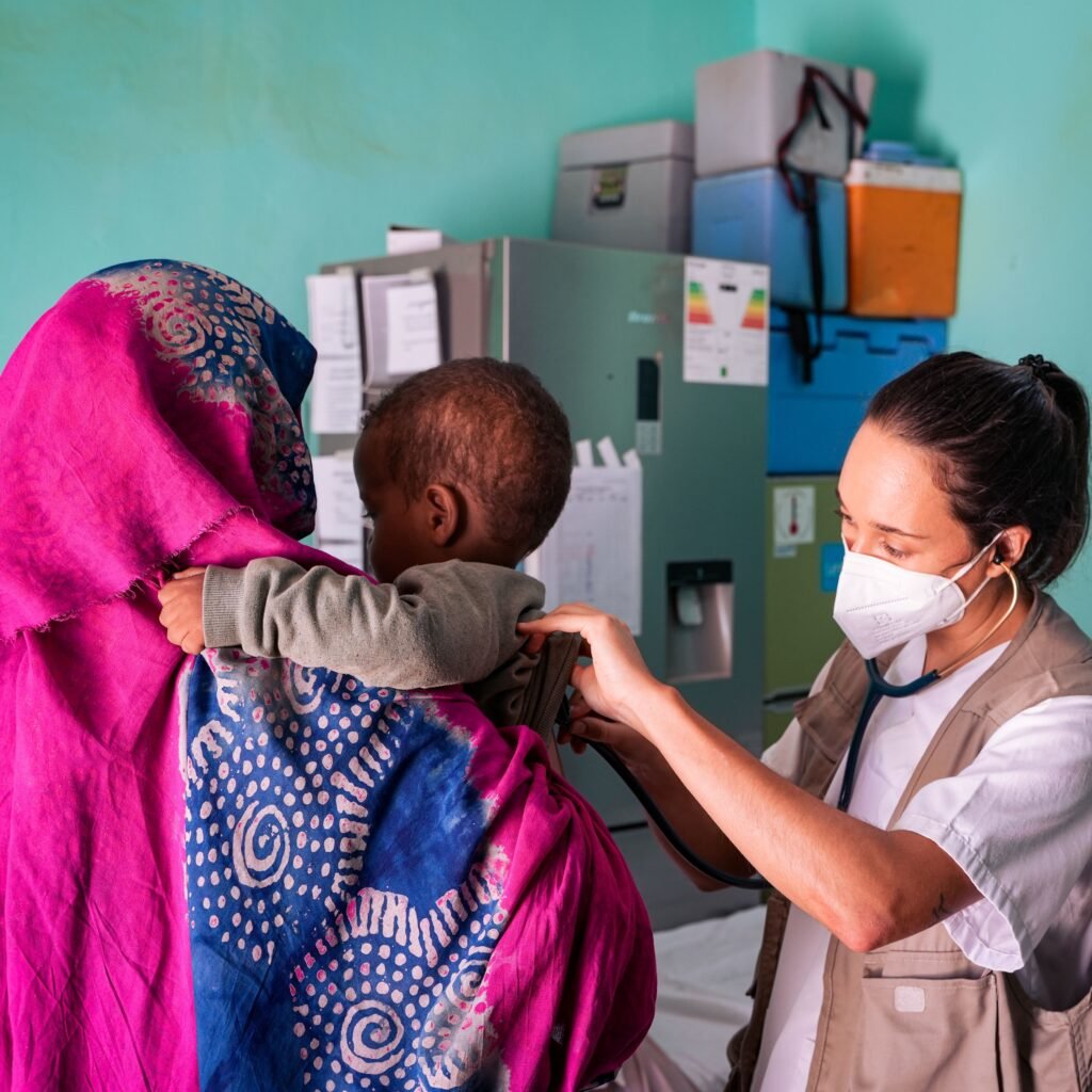 A healthcare worker examines a child held by their mother in a Tinduf clinic.