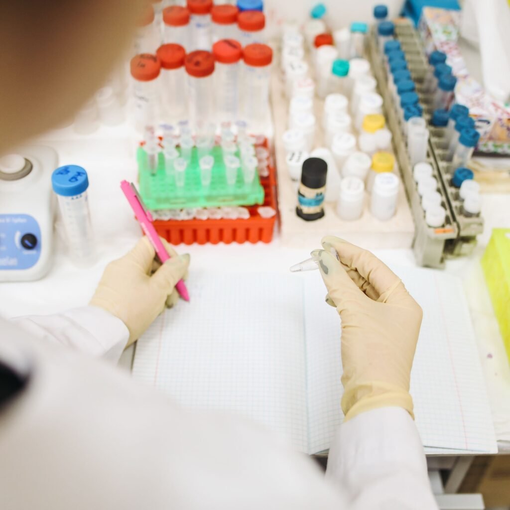 Scientist analyzing samples in a lab with various test tubes and equipment.