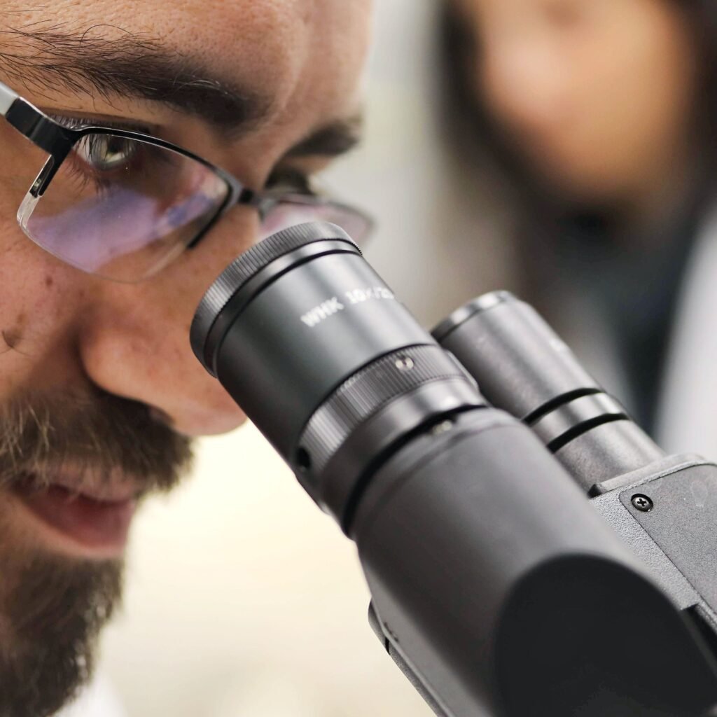 Close-up of a scientist examining samples using a microscope in a laboratory setting.