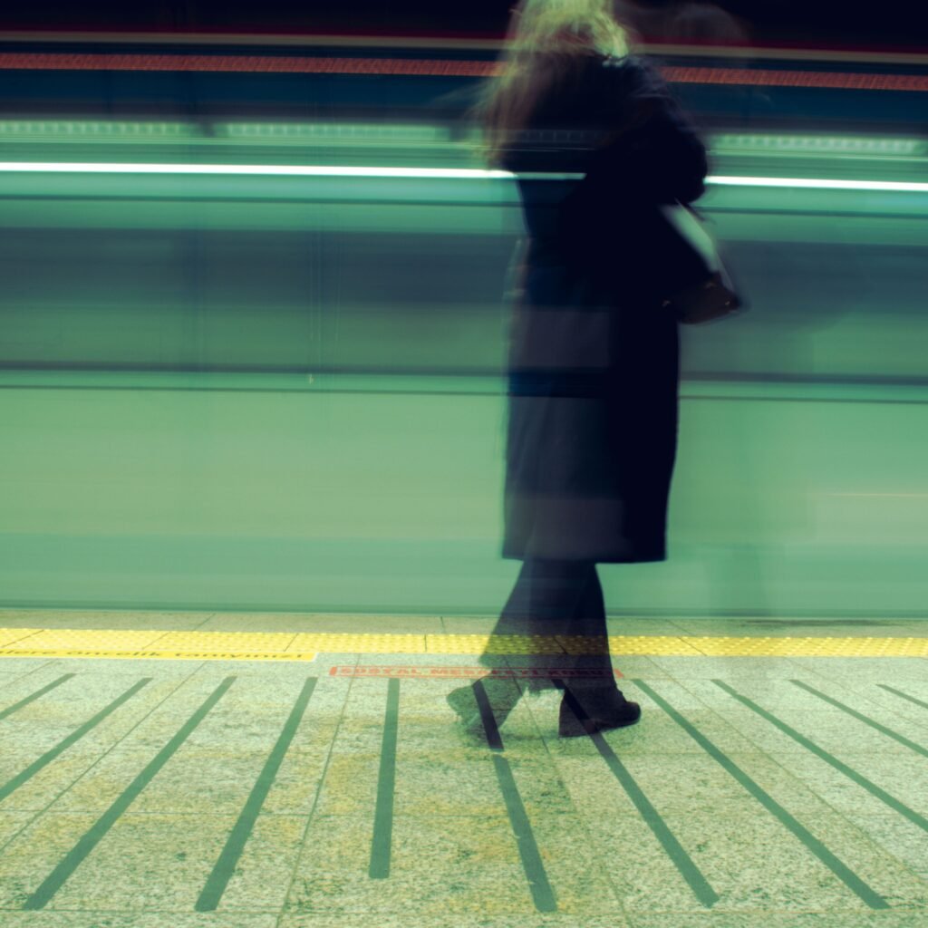 Woman waiting at Istanbul train station, blurred motion capturing a fast-moving train.