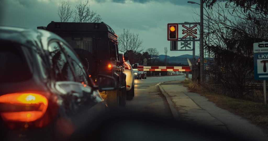 A line of cars waiting at a railway crossing during the night, showcasing urban transportation.