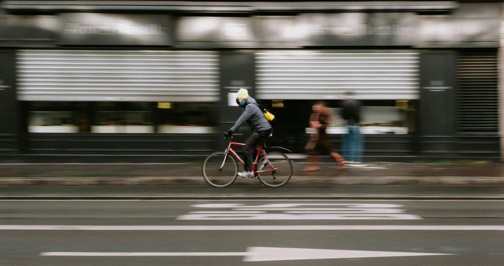 Blurry cyclist in winter jacket biking swiftly on a city street showcasing motion blur.