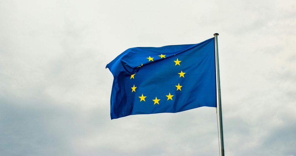 European Union flag waving vividly against a cloudy sky in Strasbourg, France.