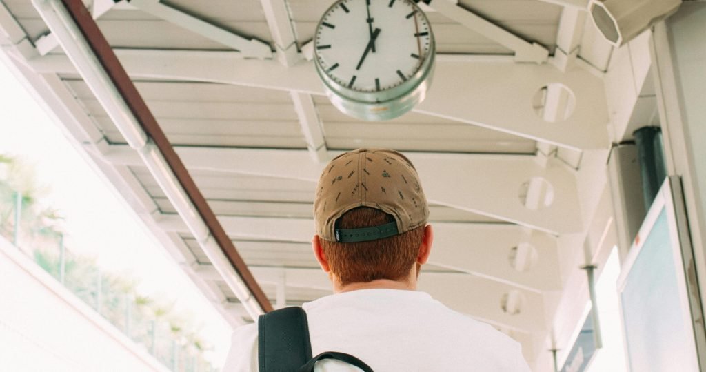 Traveler at a train station platform looking at the clock, anticipating departure.