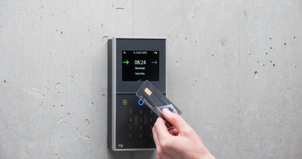 A businessman uses a secure card reader access system against a concrete wall.