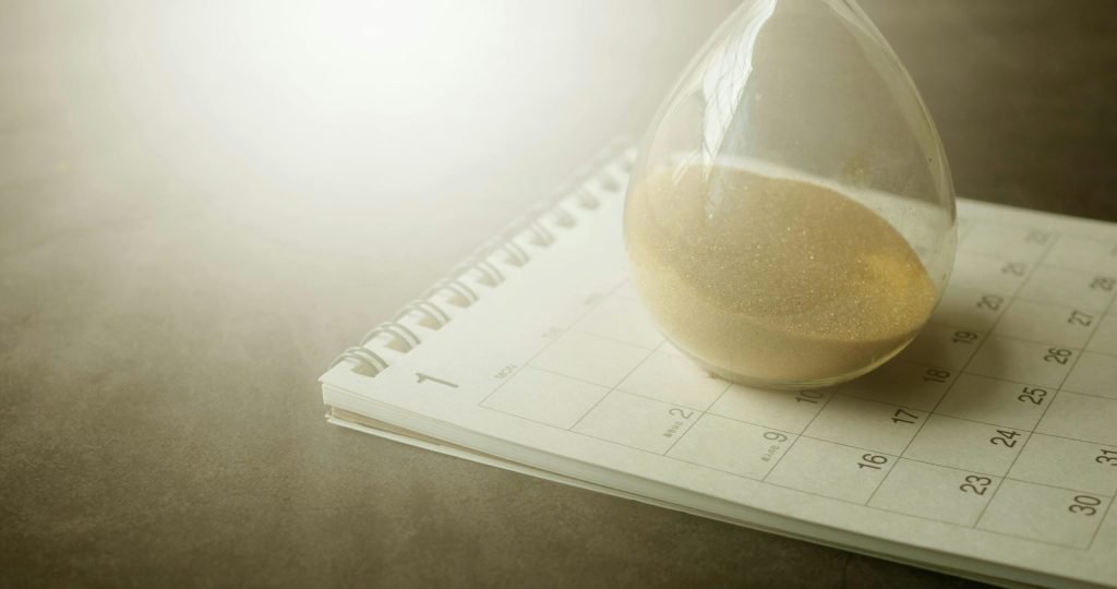 An hourglass on a calendar captures the essence of time management and urgency.