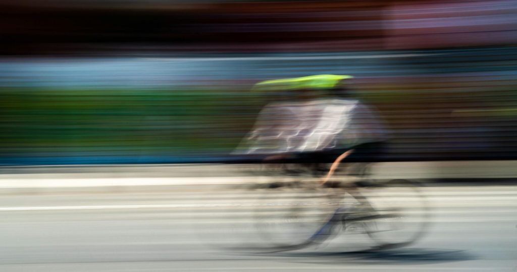 A cyclist in motion creates a blur effect on a sunny day in Mexico City.