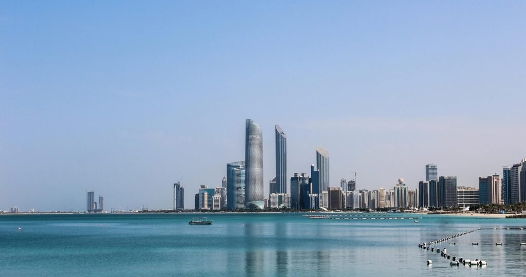 Stunning view of the Abu Dhabi skyline reflecting in the calm Gulf waters on a sunny day.