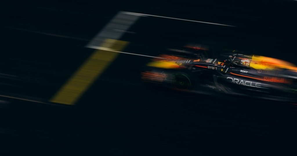 Blurred image of a Formula One car racing down the track, showcasing speed and motion.