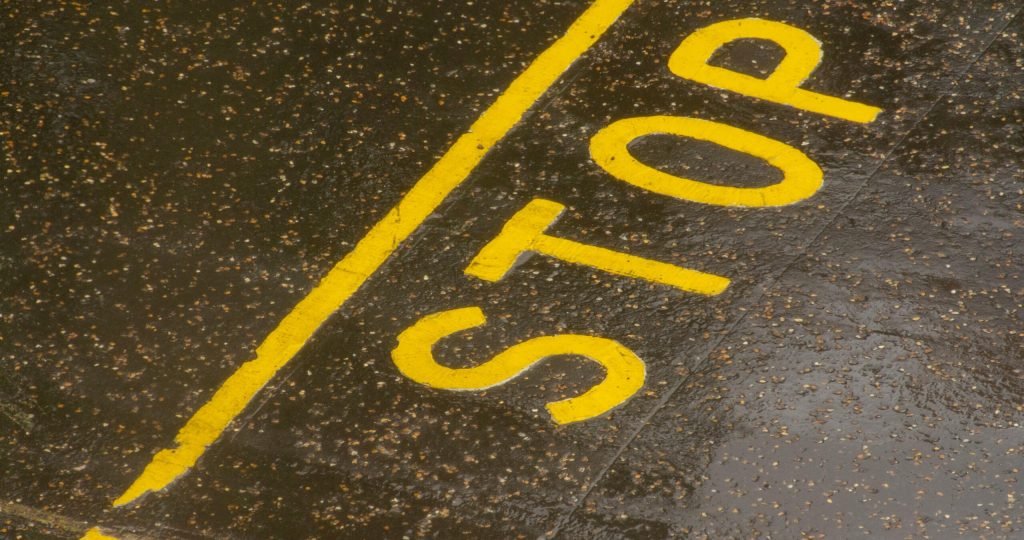 Rain-soaked road with a painted yellow STOP sign for traffic control.