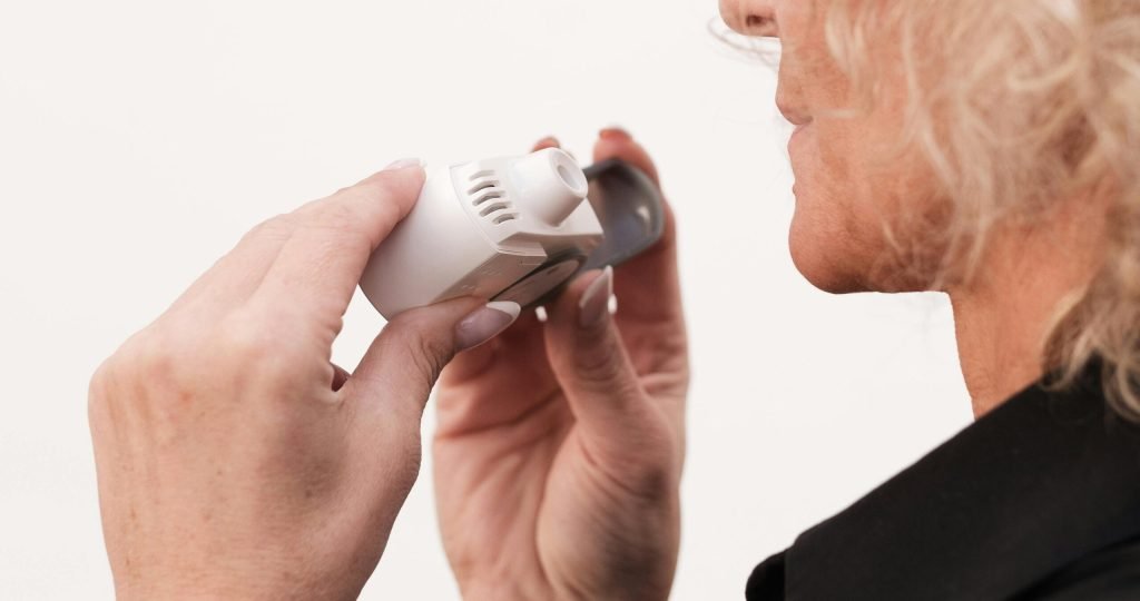 Close-up of a woman using an asthma inhaler for respiratory relief.