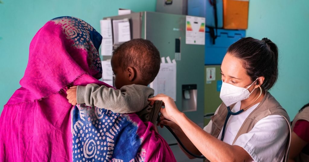 A healthcare worker examines a child held by their mother in a Tinduf clinic.