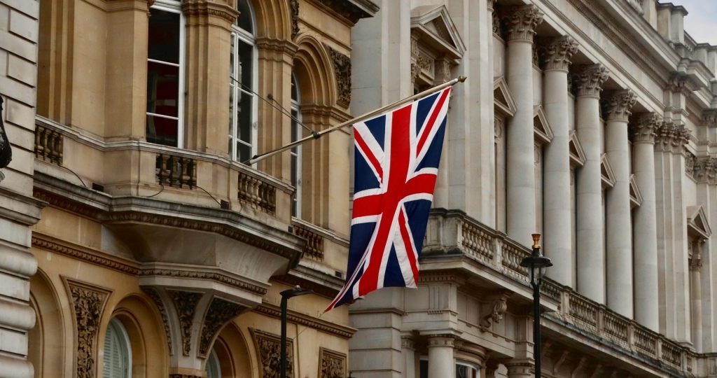 Union Jack flag flying on a historic London building facade.