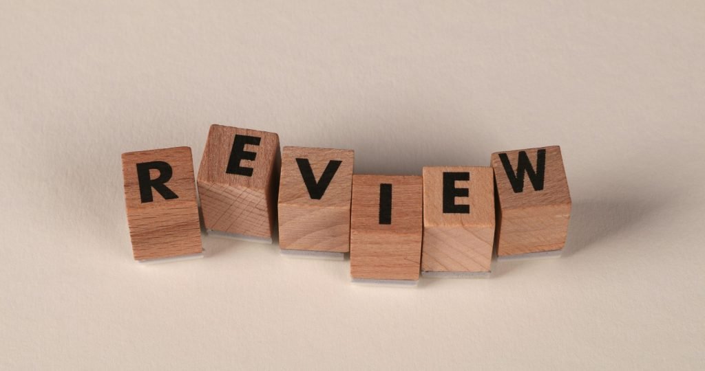 Wooden blocks with letters forming the word 'Review' on a soft pastel background.