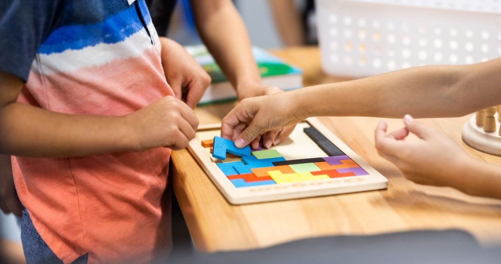 Young children learning with colorful puzzle pieces in a classroom setting.