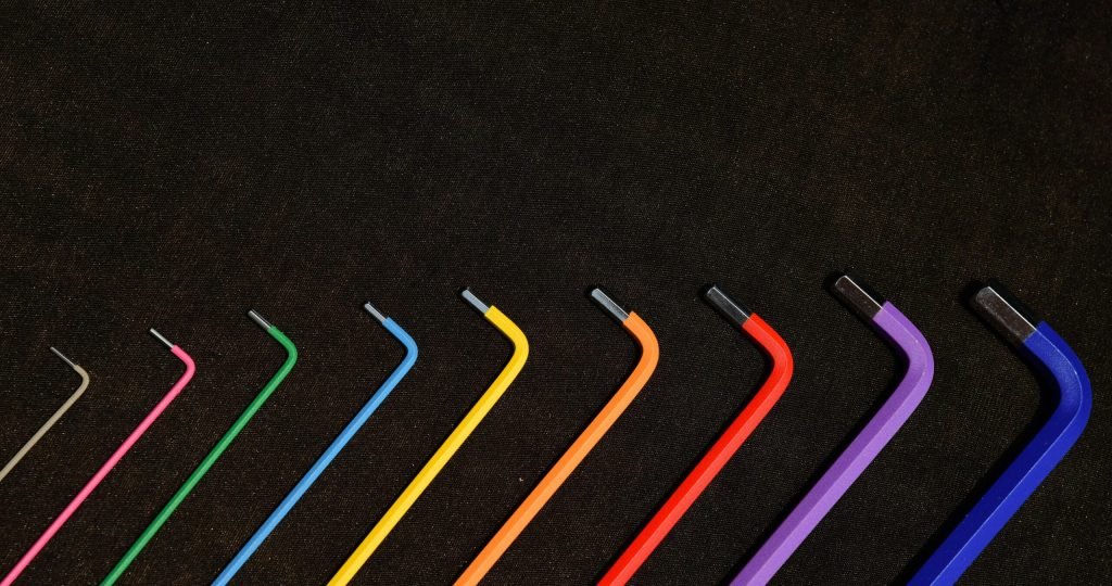 Vibrant set of hex keys in rainbow colors organized in a neat pattern on a dark backdrop.