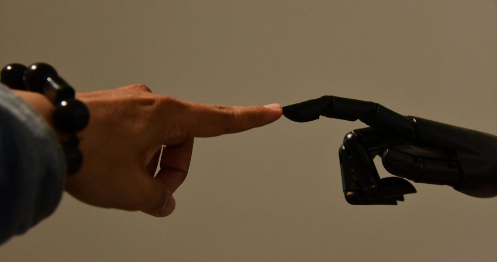 A human hand and a robotic hand extending fingers to touch, symbolizing connection.