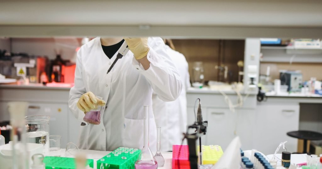 Scientist in a lab coat handling samples for scientific research in a modern laboratory setting.