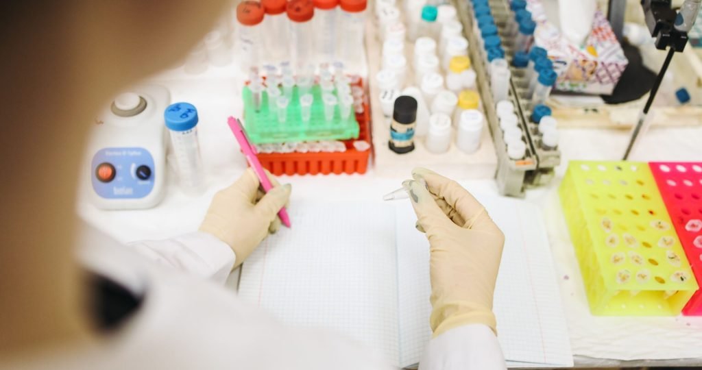 Scientist analyzing samples in a lab with various test tubes and equipment.