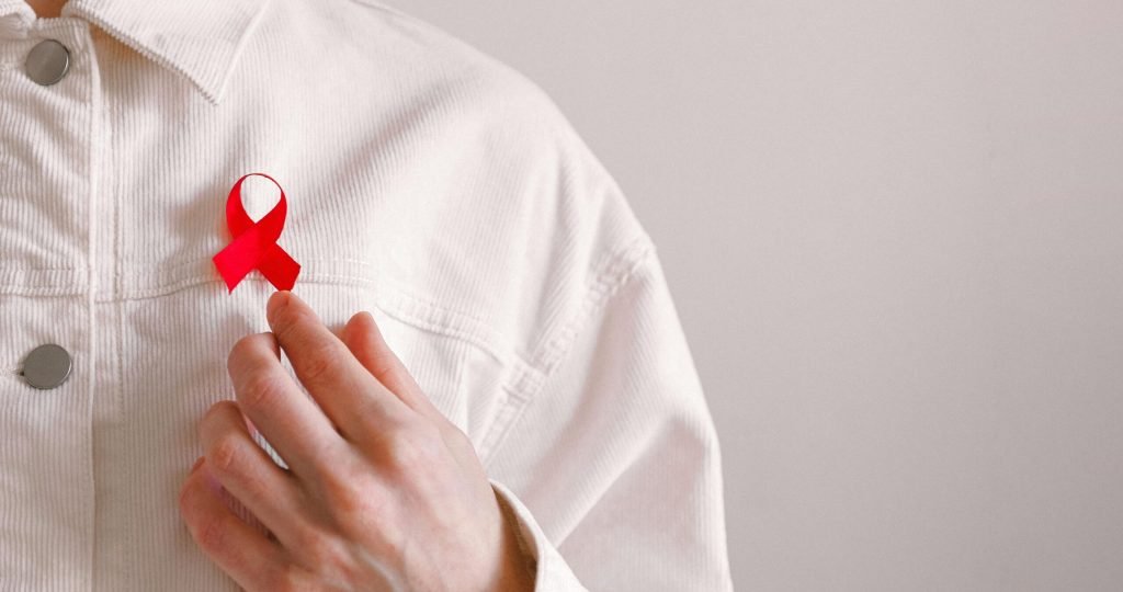 Close-up of a red ribbon on a white shirt symbolizing AIDS awareness and support.