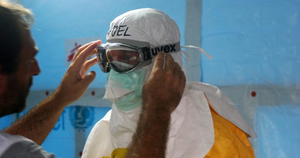 Healthcare worker puts on PPE gear in a medical facility for safety and protection.