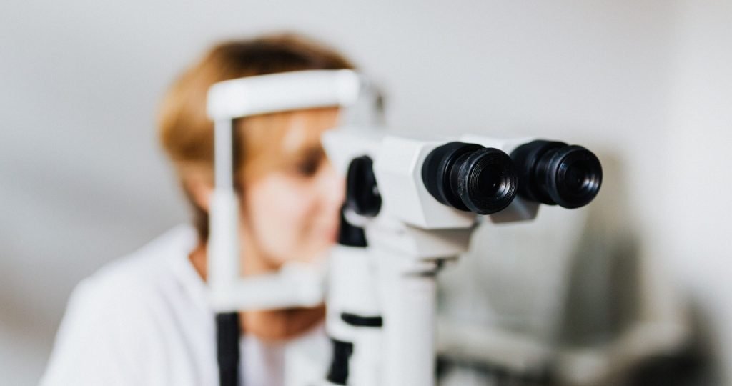 Close-up of an eye examination using a slit lamp machine in a clinical setting.
