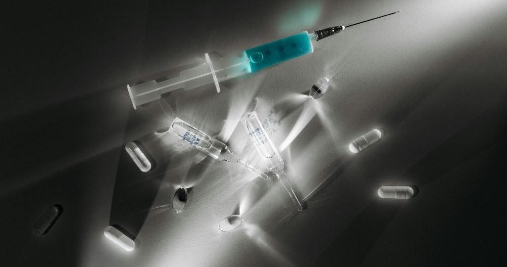 High contrast image of medical supplies, including a syringe and capsules, in a monochrome setting.