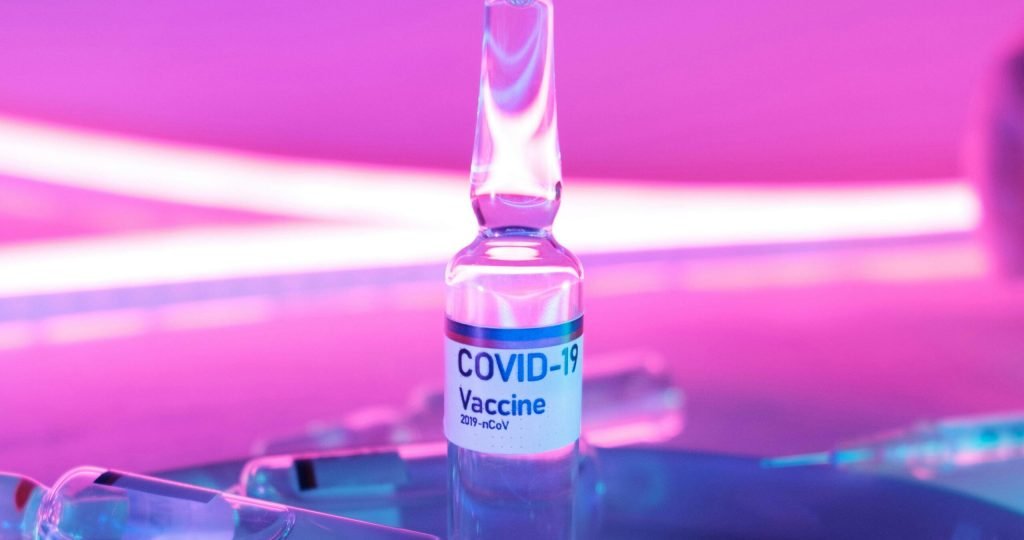 Ampoule with vaccine for injection for COVID 19 in laboratory in bright purple light