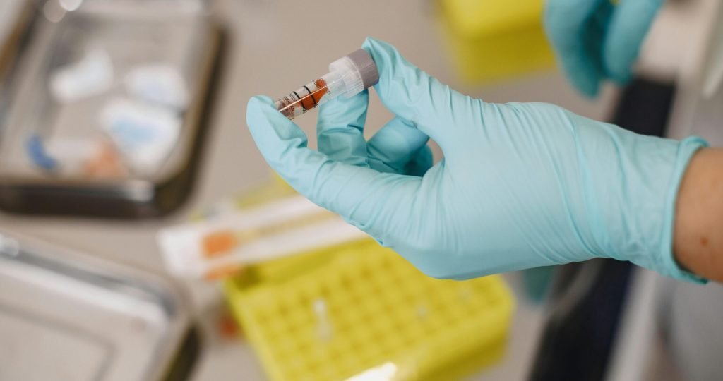 Close-up of a scientist's hand holding a test tube with protective gloves in a lab.