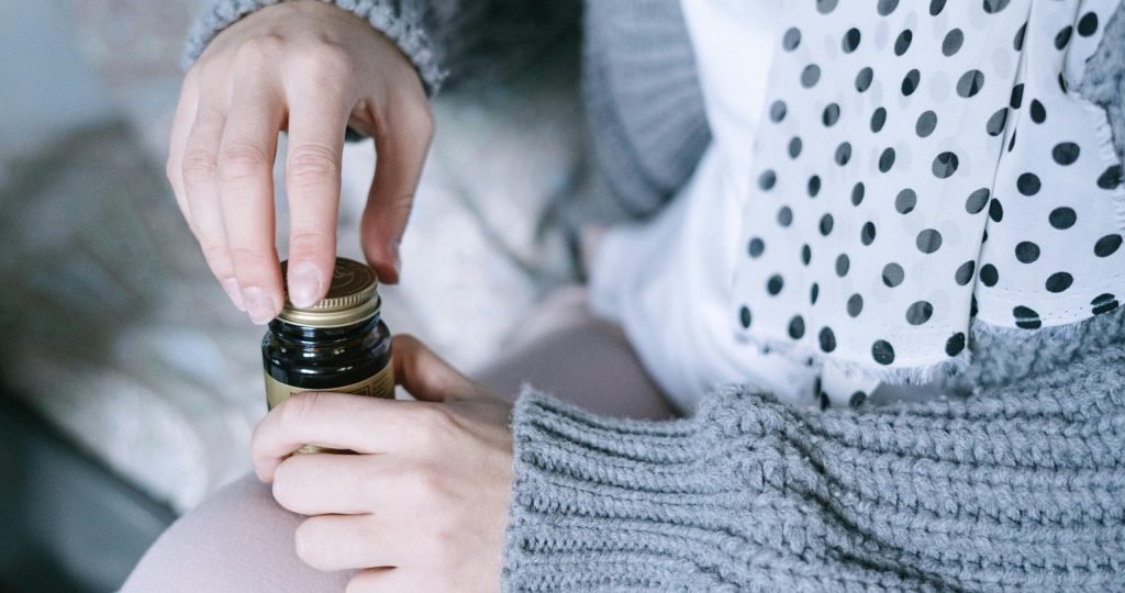 A close-up of hands opening a medicine bottle, emphasizing healthcare and recovery.