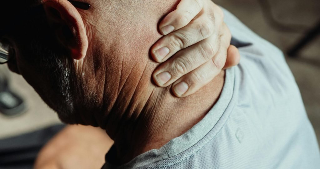 Man with neck pain holding his neck in discomfort, conveying tension or stress.