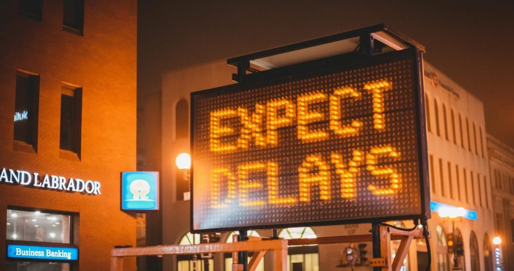Mobile electronic traffic sign with inscription Expect delays placed on road in city street in evening time