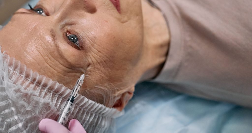 A senior woman undergoes a cosmetic injection procedure in a medical facility.