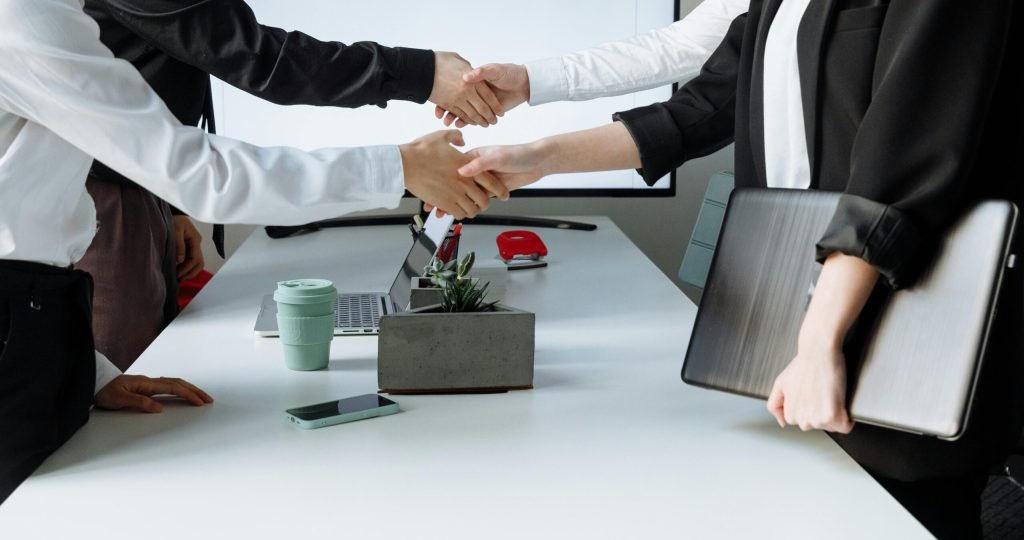 Professionals sealing a deal with a handshake across a conference table during a business meeting.