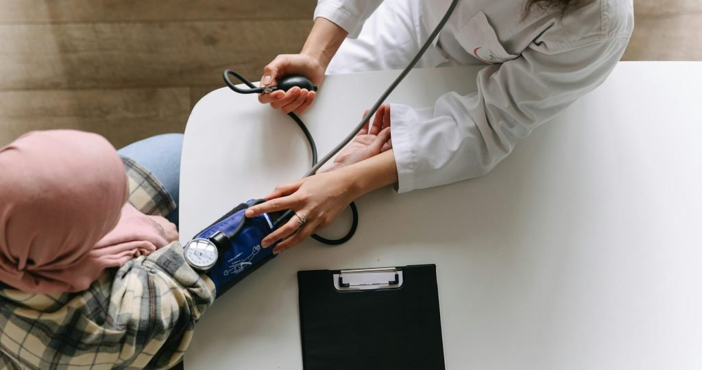 A medical practitioner checks a patient's blood pressure in a clinical setting, showcasing healthcare service.