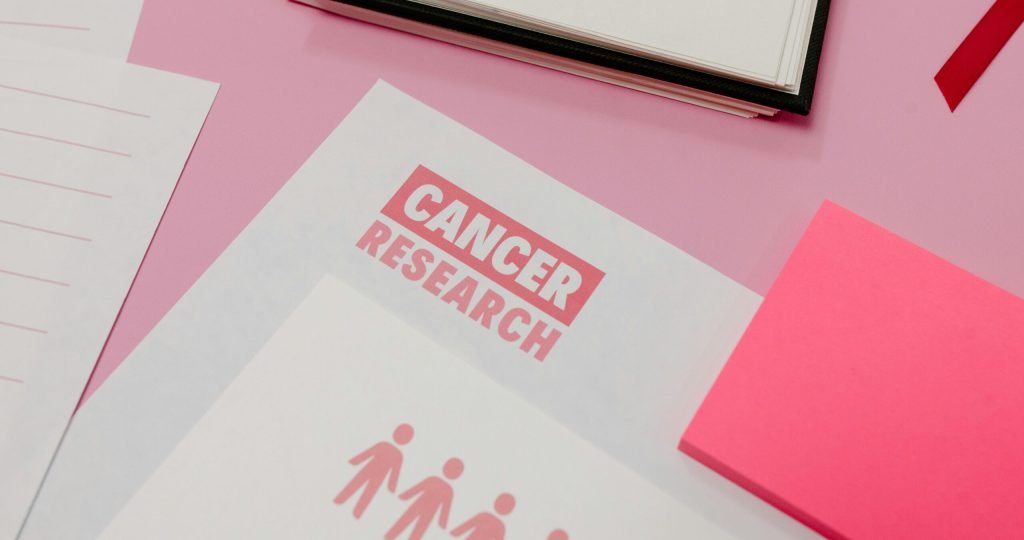 Assorted cancer research materials laid on a pink desk. Professional workspace.