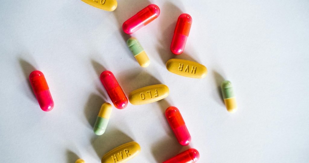 A vibrant assortment of colorful capsules and pills scattered on a white surface.