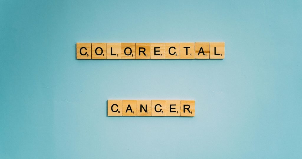 Scrabble tiles spell 'Colorectal Cancer' on a light blue background for cancer awareness.