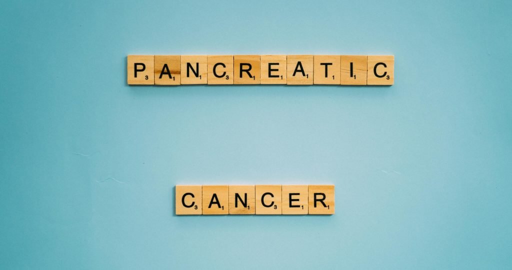 Wooden tiles spelling pancreatic cancer on blue. Health awareness concept.