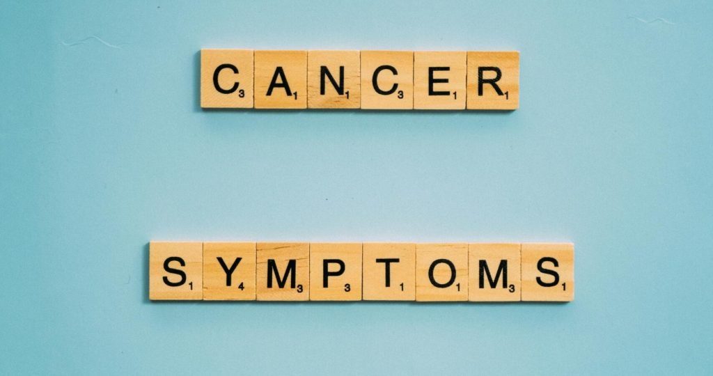Scrabble tiles spelling 'cancer symptoms' on a blue background, emphasizing awareness.