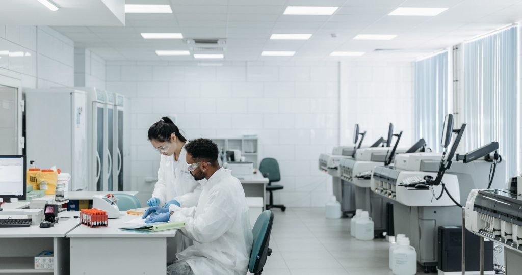 Scientists in a laboratory analyzing samples with advanced equipment and protective gear.