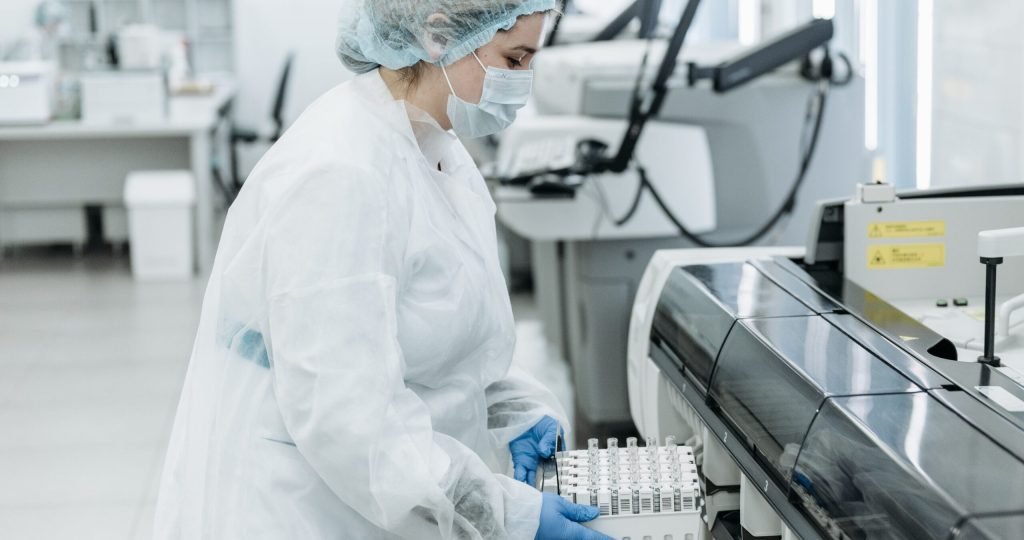 Laboratory scientist in protective gear working with medical samples.