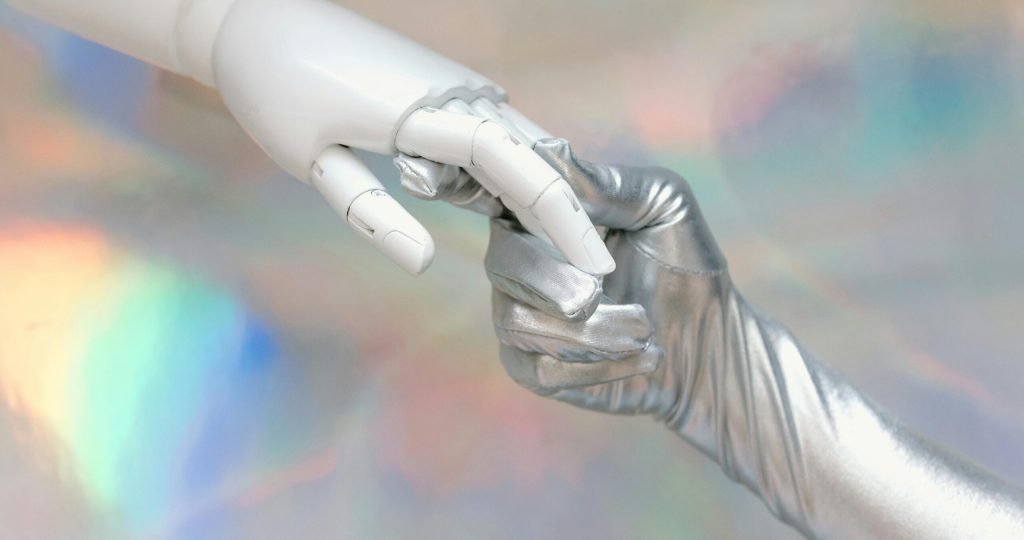 Close-up of a robot hand and silver-gloved hand touching, symbolizing human-robot connection.