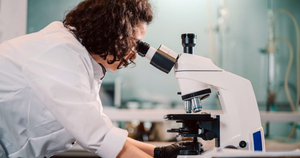 A woman scientist using a microscope in a laboratory setting.
