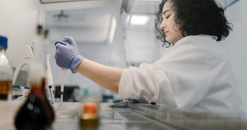 Woman in lab coat conducting research with pipette in modern laboratory.