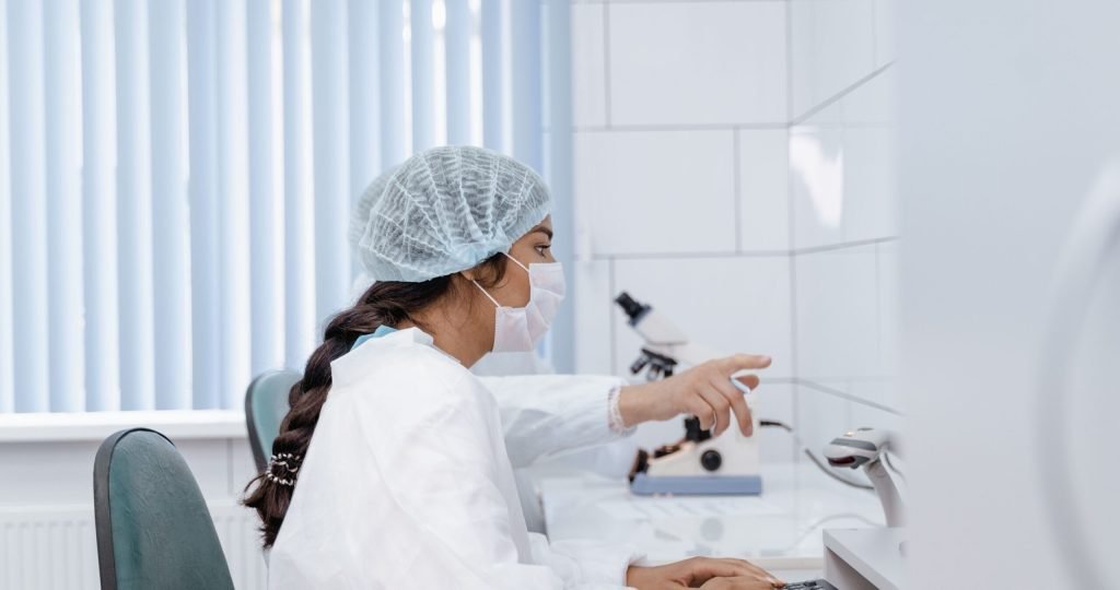 Female scientist in laboratory coat working at computer in a clean, modern lab.