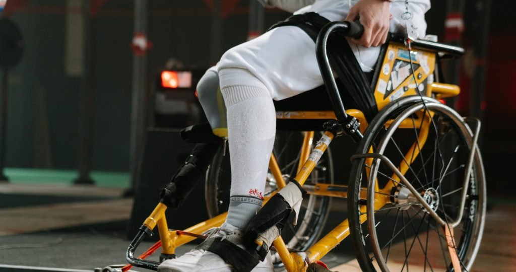 Focused athlete in wheelchair fencing gear, showcasing strength and determination.